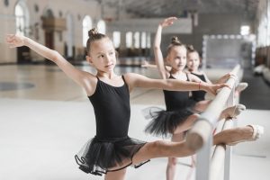 ballerina girls black tutu stretching their legs bar