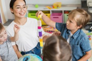 woman teaching children how play with colorful tower